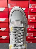 Light gray Air Jordan 4 sneaker toe view with lace-up closure, textured toe and yellow midsole tab