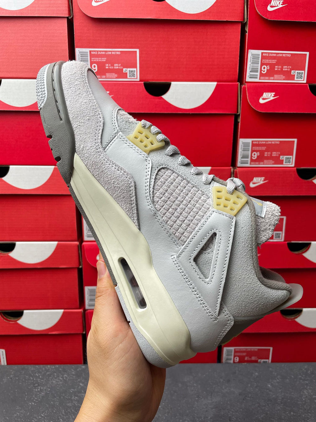 Light gray Air Jordan 4 sneaker front side view with quilted upper, yellow net details