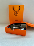 Taupe leather belt displayed in box with silver double-prong buckle