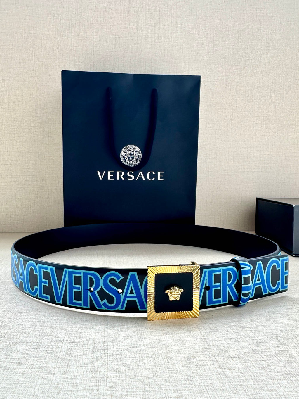 Versace logo belt with blue webbing, gold buckle and Medusa emblem.