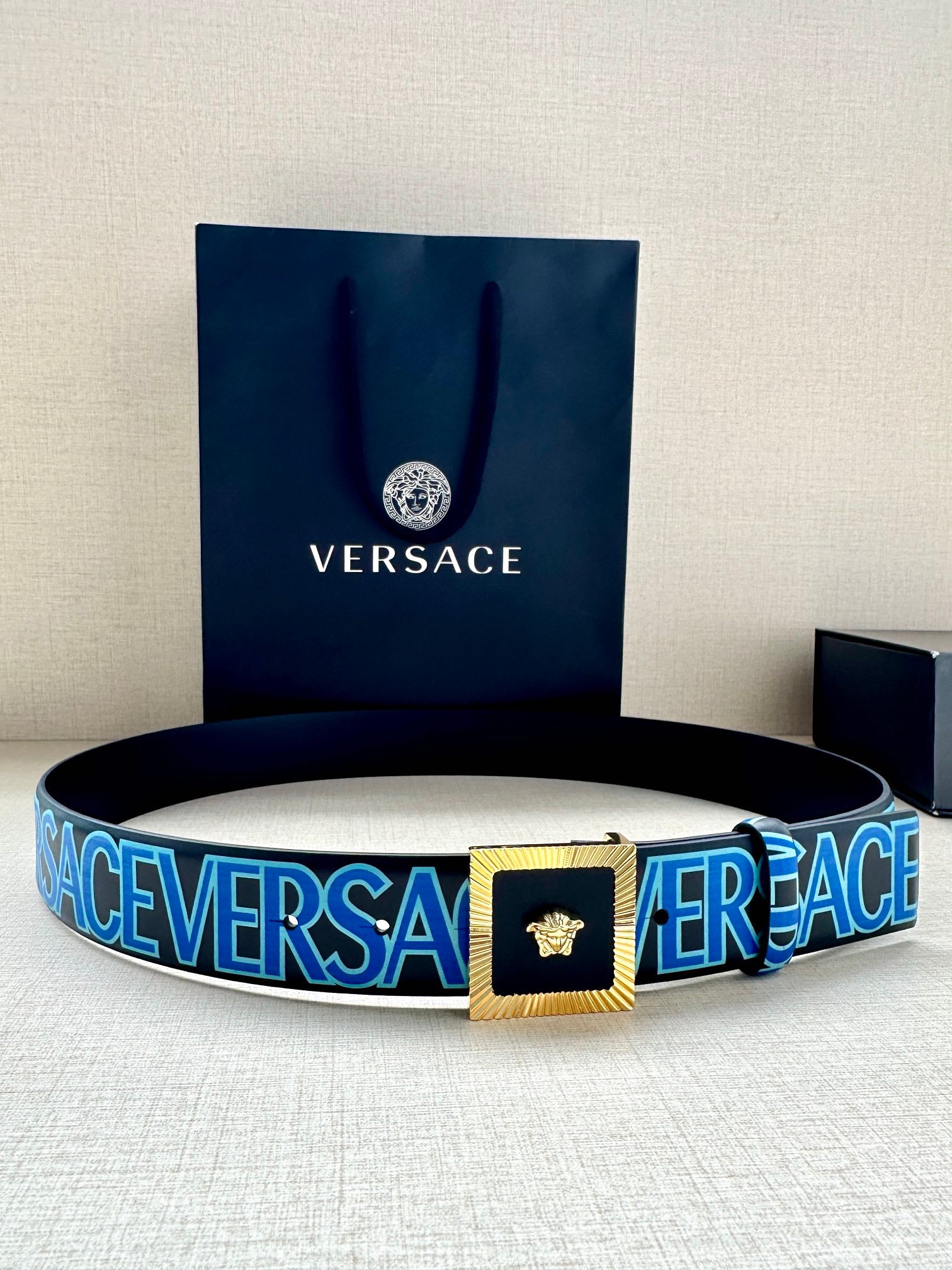 Versace logo belt with blue webbing, gold buckle and Medusa emblem.