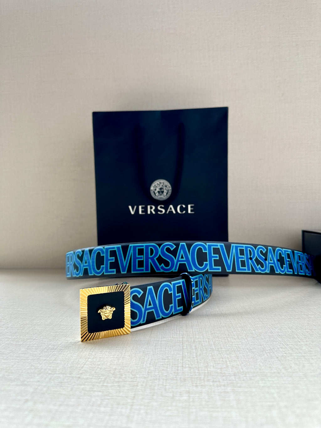 Versace logo belt on display, blue pattern strap with gold buckle and Medusa.