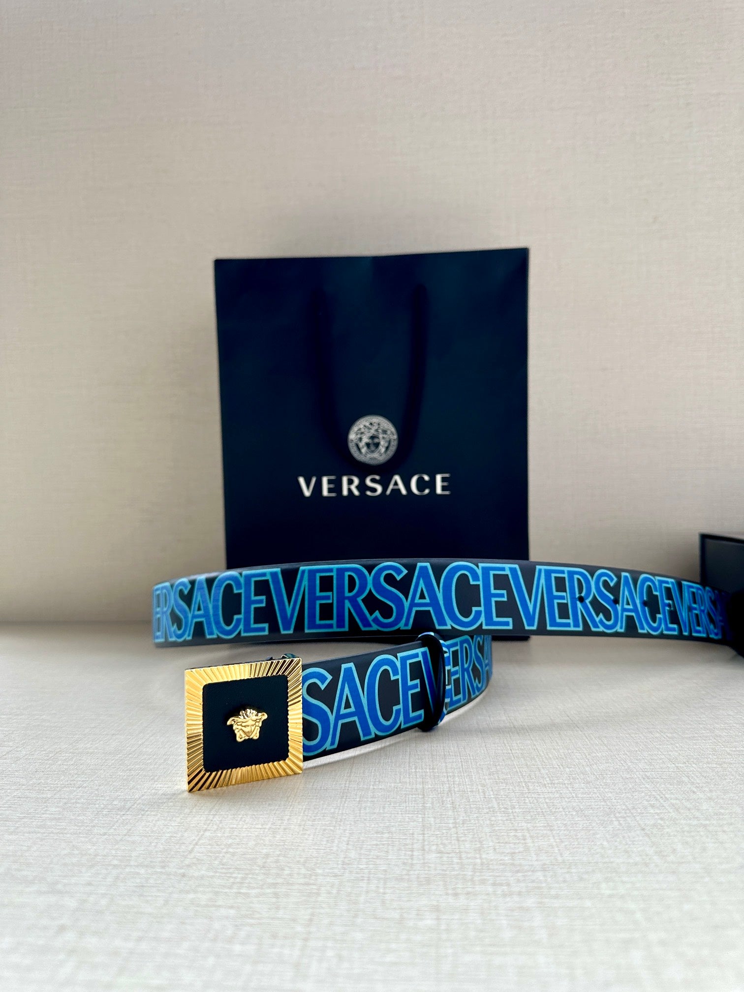 Versace logo belt on display, blue pattern strap with gold buckle and Medusa.