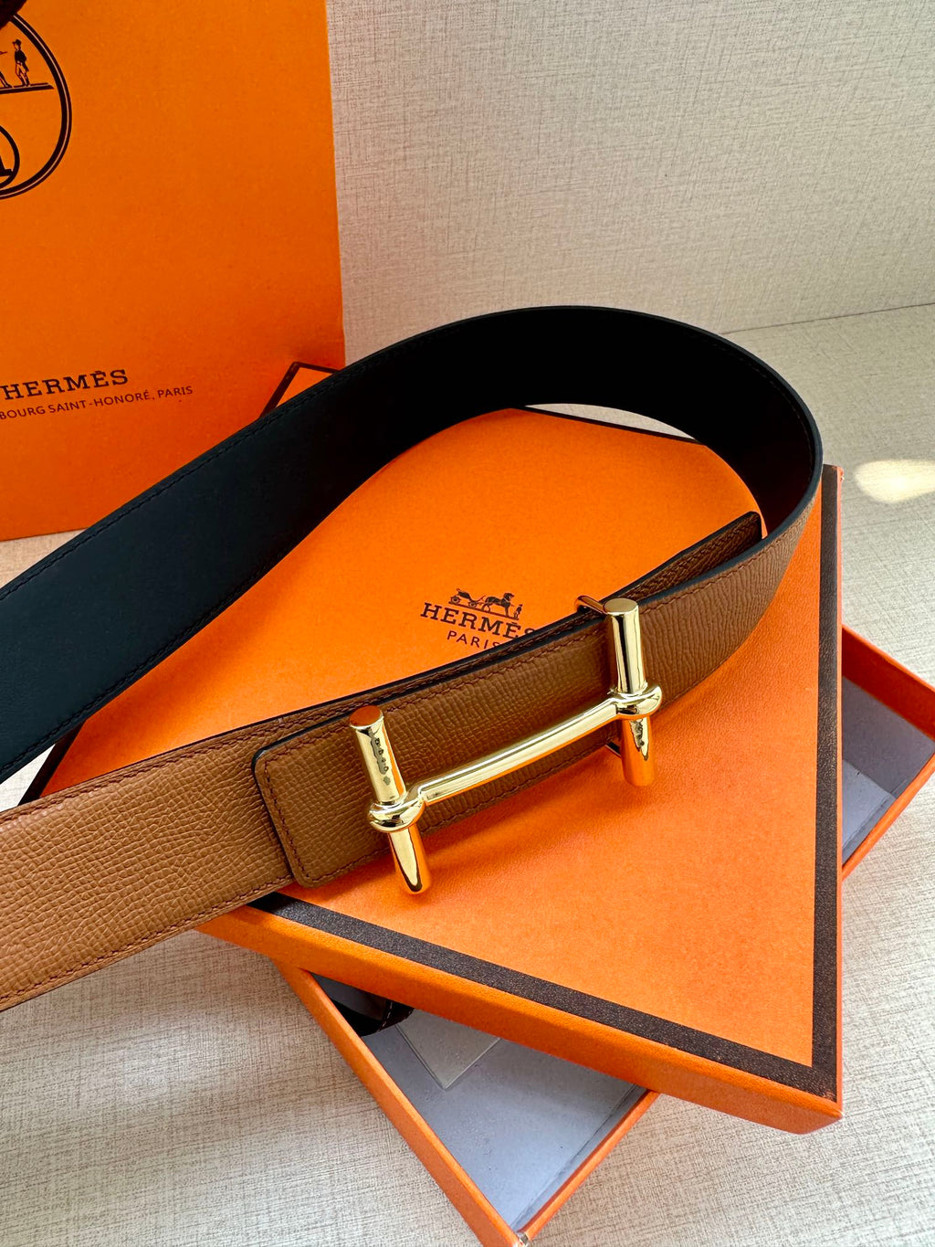 Hermes leather belt with tan and dark leather panels and silver buckle, angled view