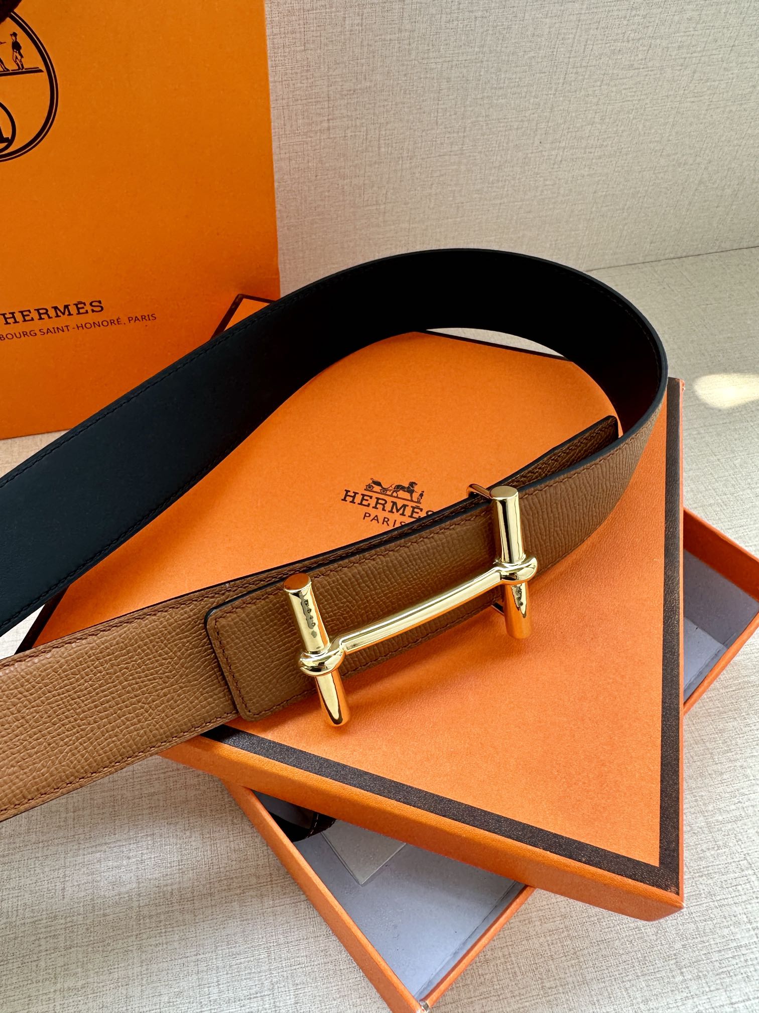 Hermes leather belt with tan and dark leather panels and silver buckle, angled view
