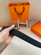 Hermes reversible leather belt, tan and dark panels with silver buckle, hand holding