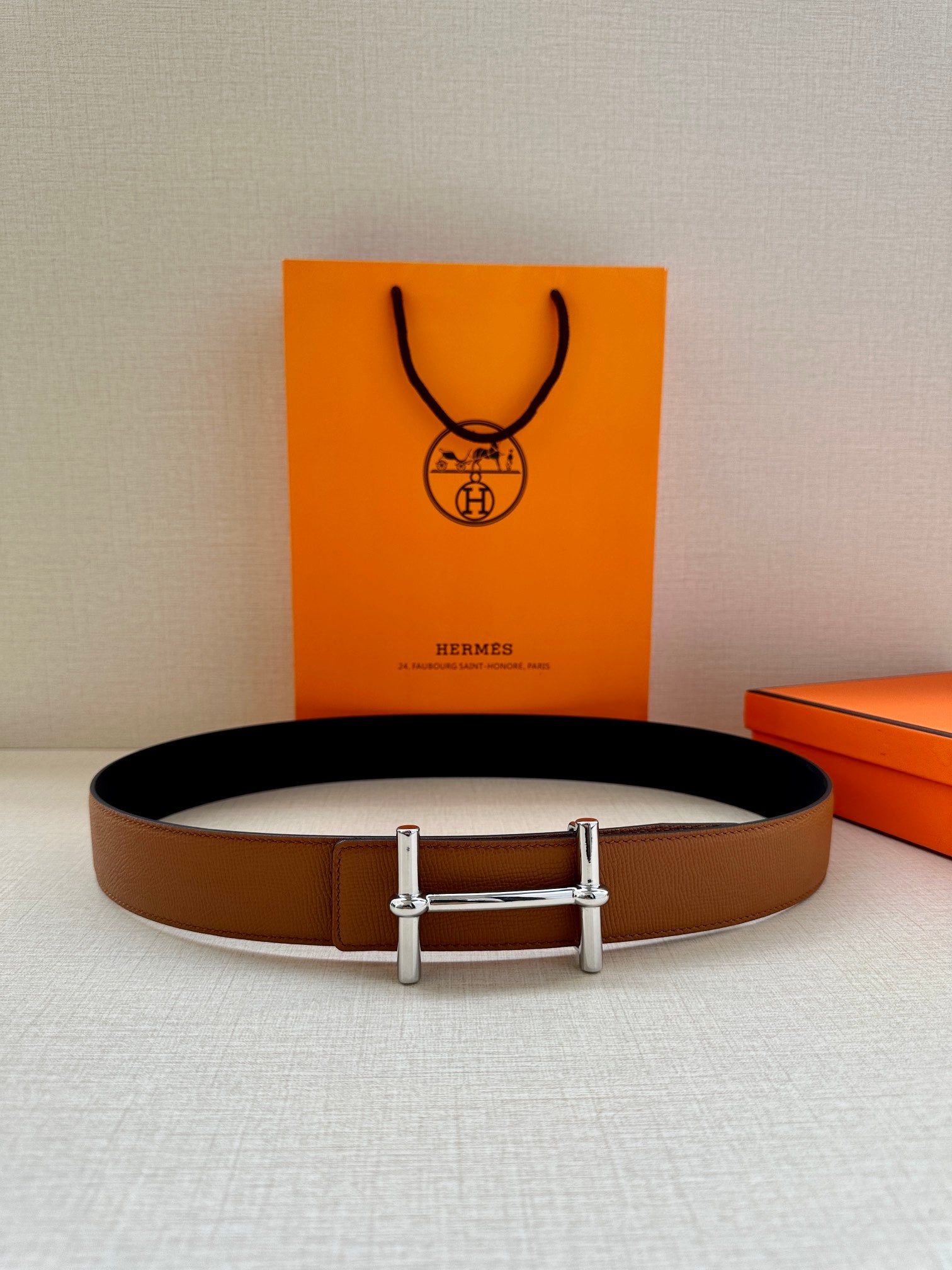 Hermes leather belt in tan with silver double-prong buckle, laid flat view