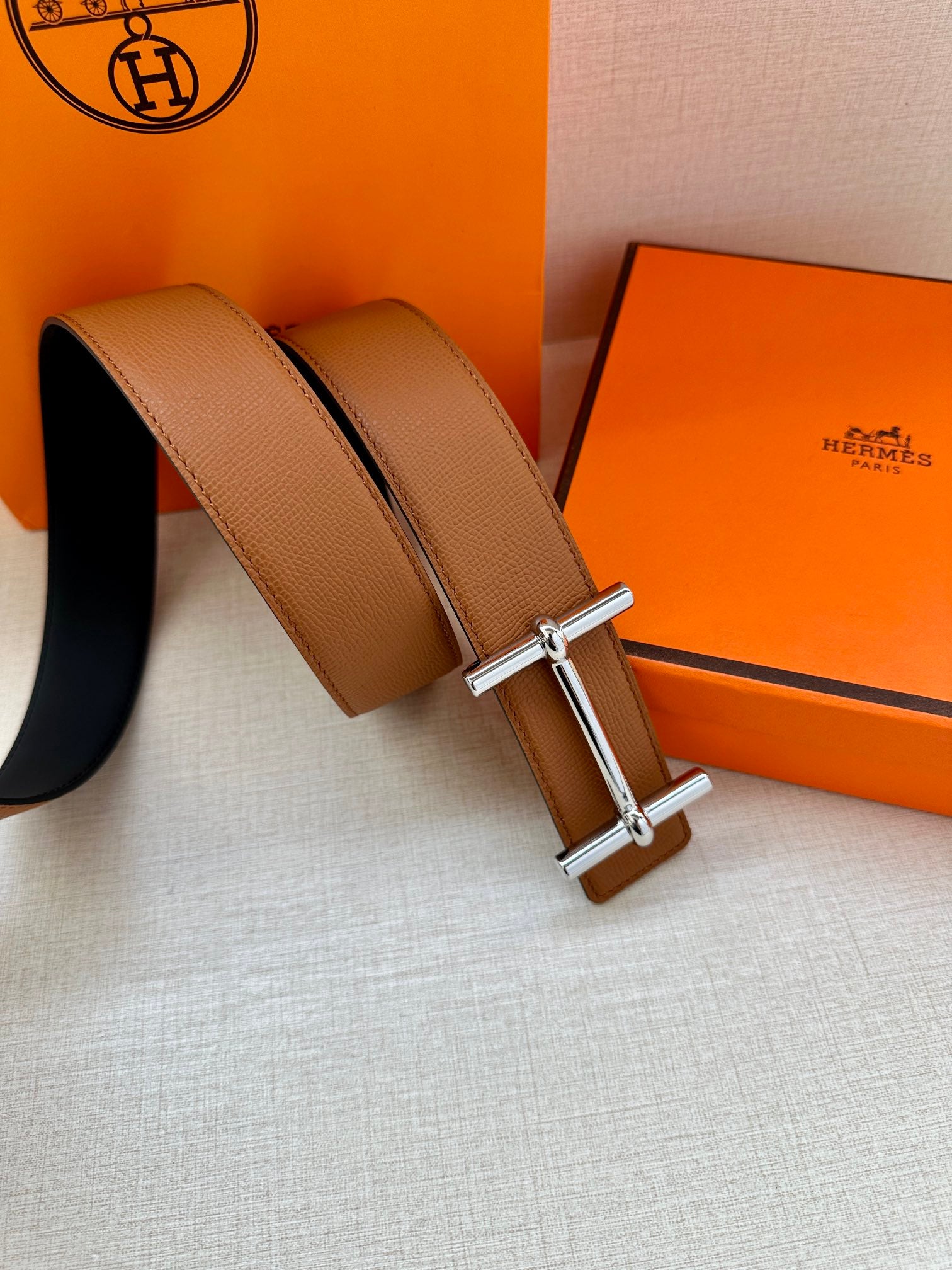 Hermes leather belt with tan strap and silver buckle, two strap lengths visible