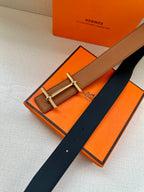 Hermes leather belt in tan with silver buckle and navy underside, flat on surface