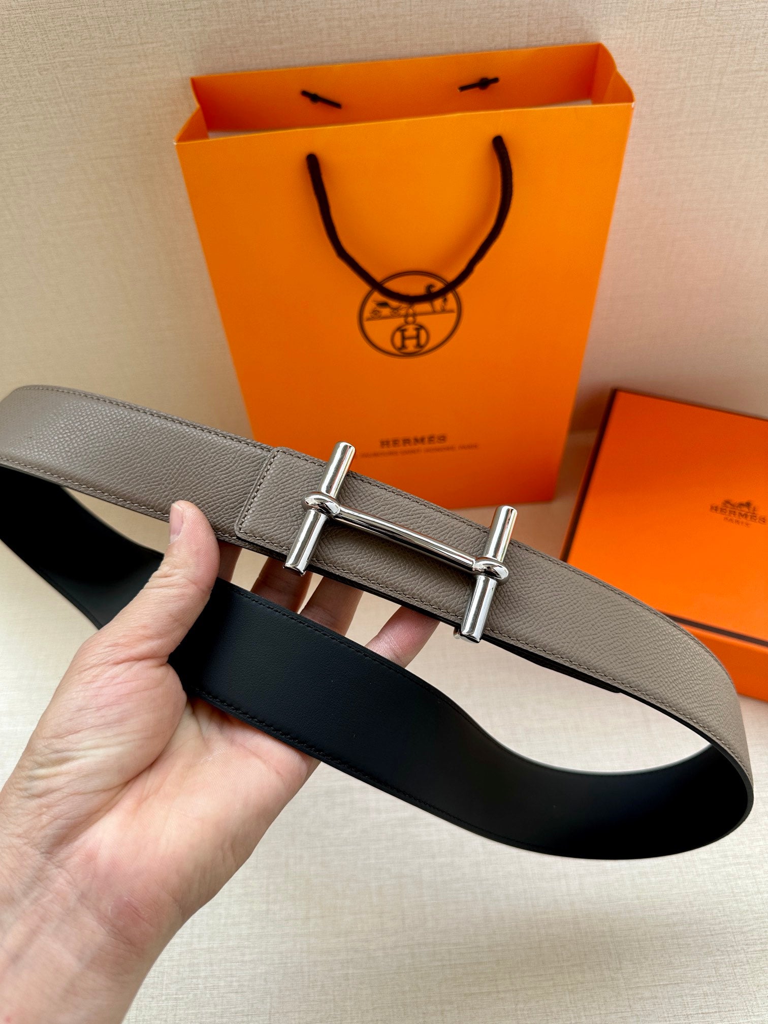 Gray leather belt with silver double-bar buckle and black underside