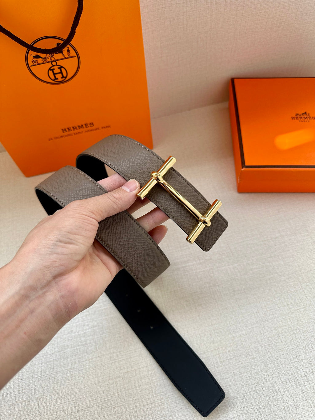 Gray leather belt with gold-toned double-bar buckle and punched adjustment holes