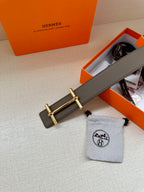 Gray leather belt with gold-toned double-bar buckle, shown near tag