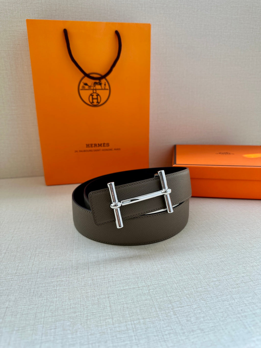 Gray leather belt with silver double-bar buckle on a curved view