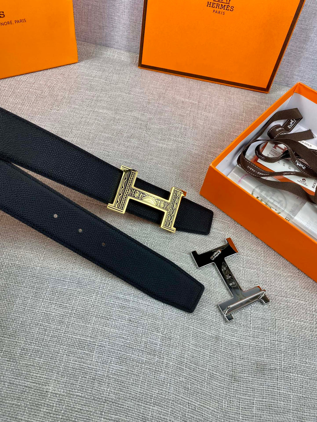 Dark leather belt with gold-tone H-shaped buckle and spare silver-tone buckle parts
