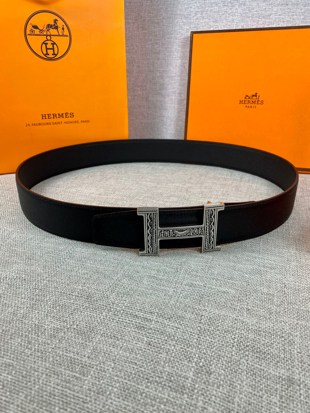 Dark leather belt with silver-tone rectangular buckle centered on light fabric