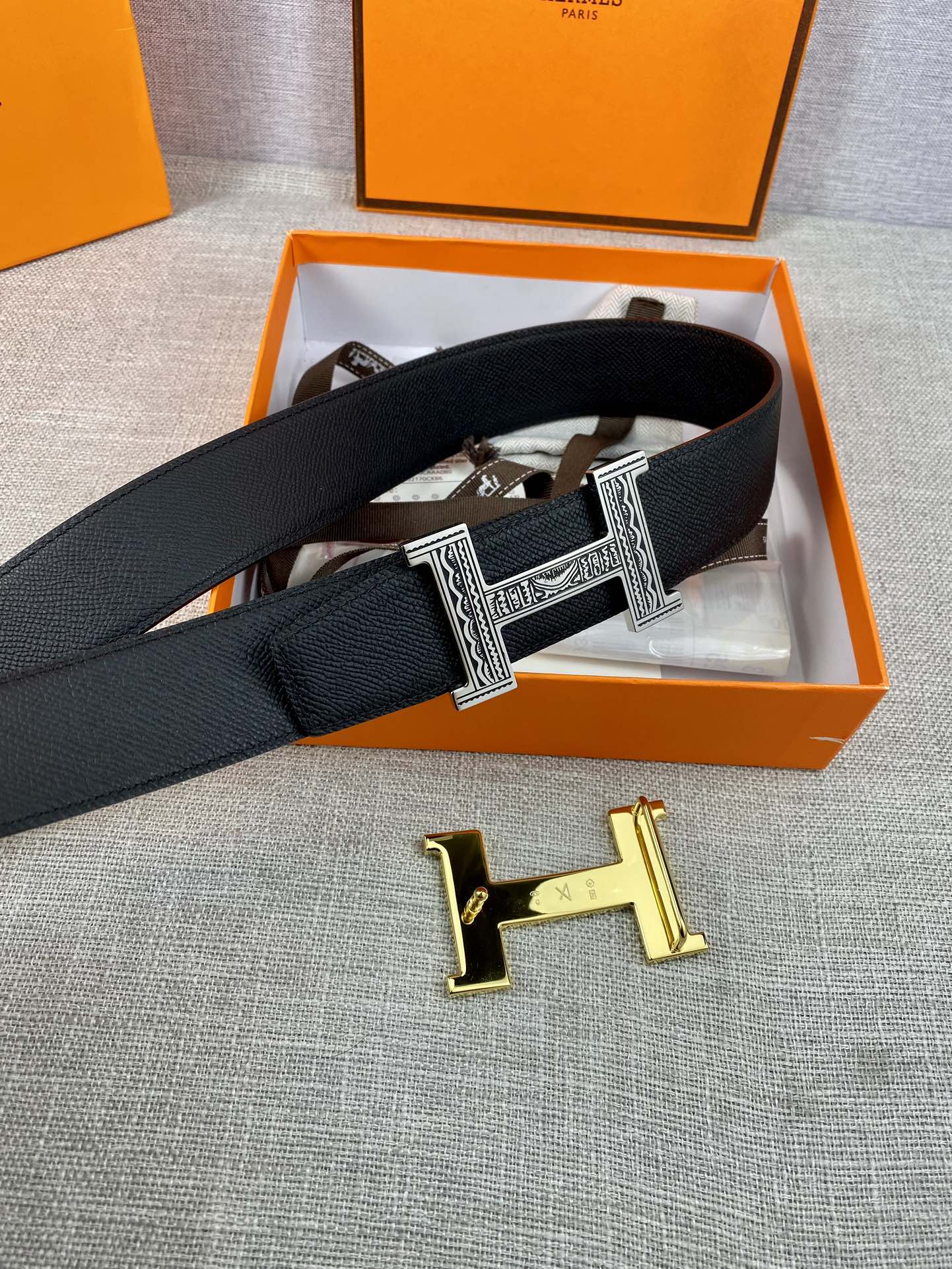 Dark leather belt with gold-tone square buckle, set in an orange box insert