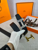 Dark leather belt with silver-tone patterned buckle, white-gloved hand holding it