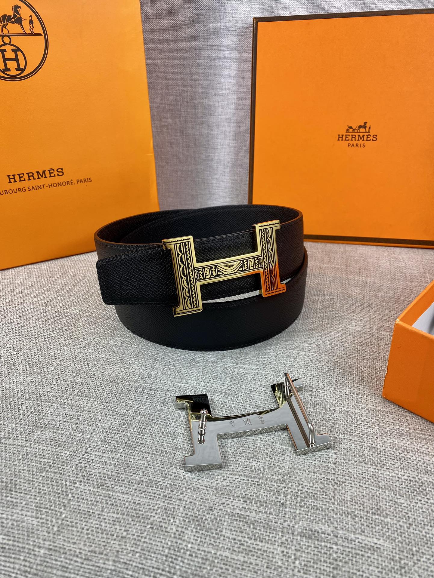 Dark leather belt with gold-tone rectangular buckle on display stand