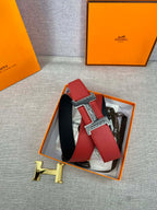 Red belt with silver engraved H buckle and black underside, displayed in orange box