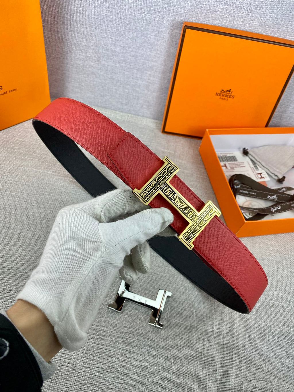 Red leather belt with black underside and silver engraved H buckle detail