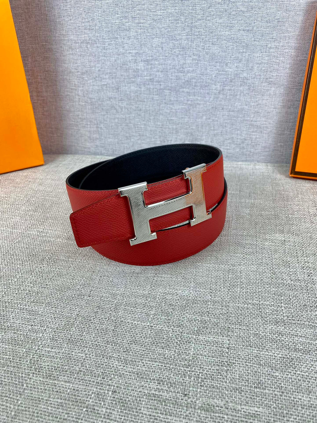 Red leather belt with silver H buckle, flat lay