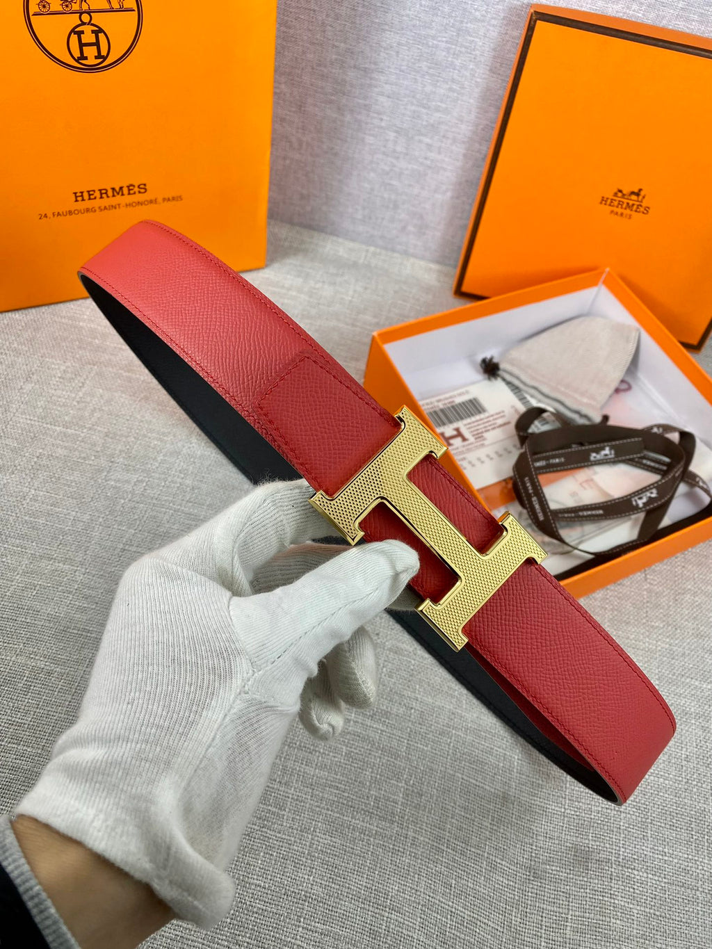 Red leather belt with gold H buckle and black underside