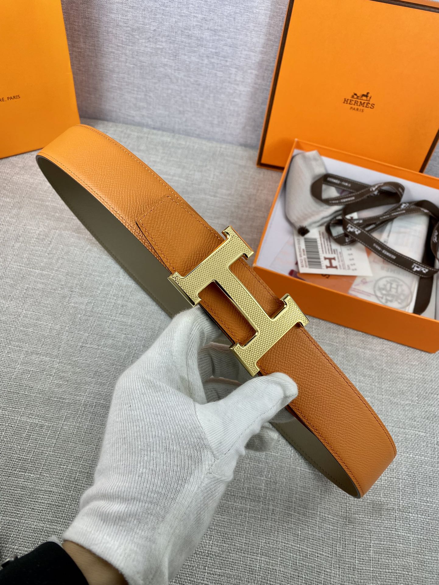 Orange leather belt with gold H buckle and olive-green keeper strap