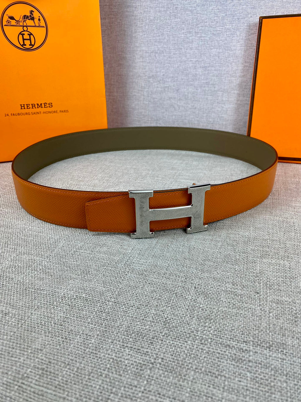Orange leather belt with silver H buckle on green strap, full view