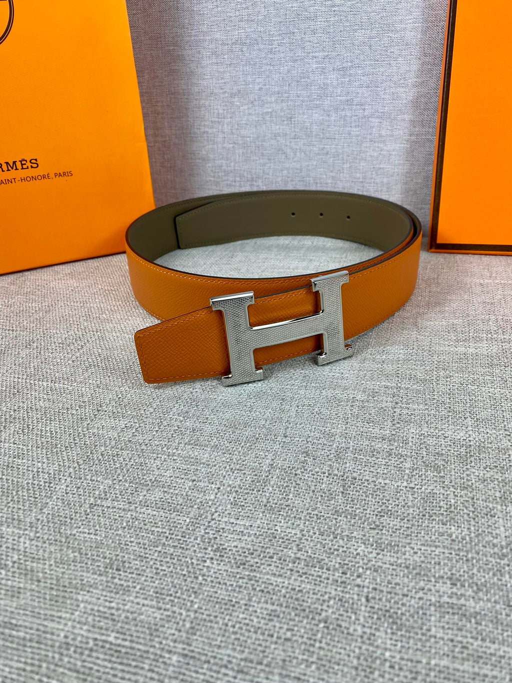 Two-tone leather belt with large silver H buckle on olive strap