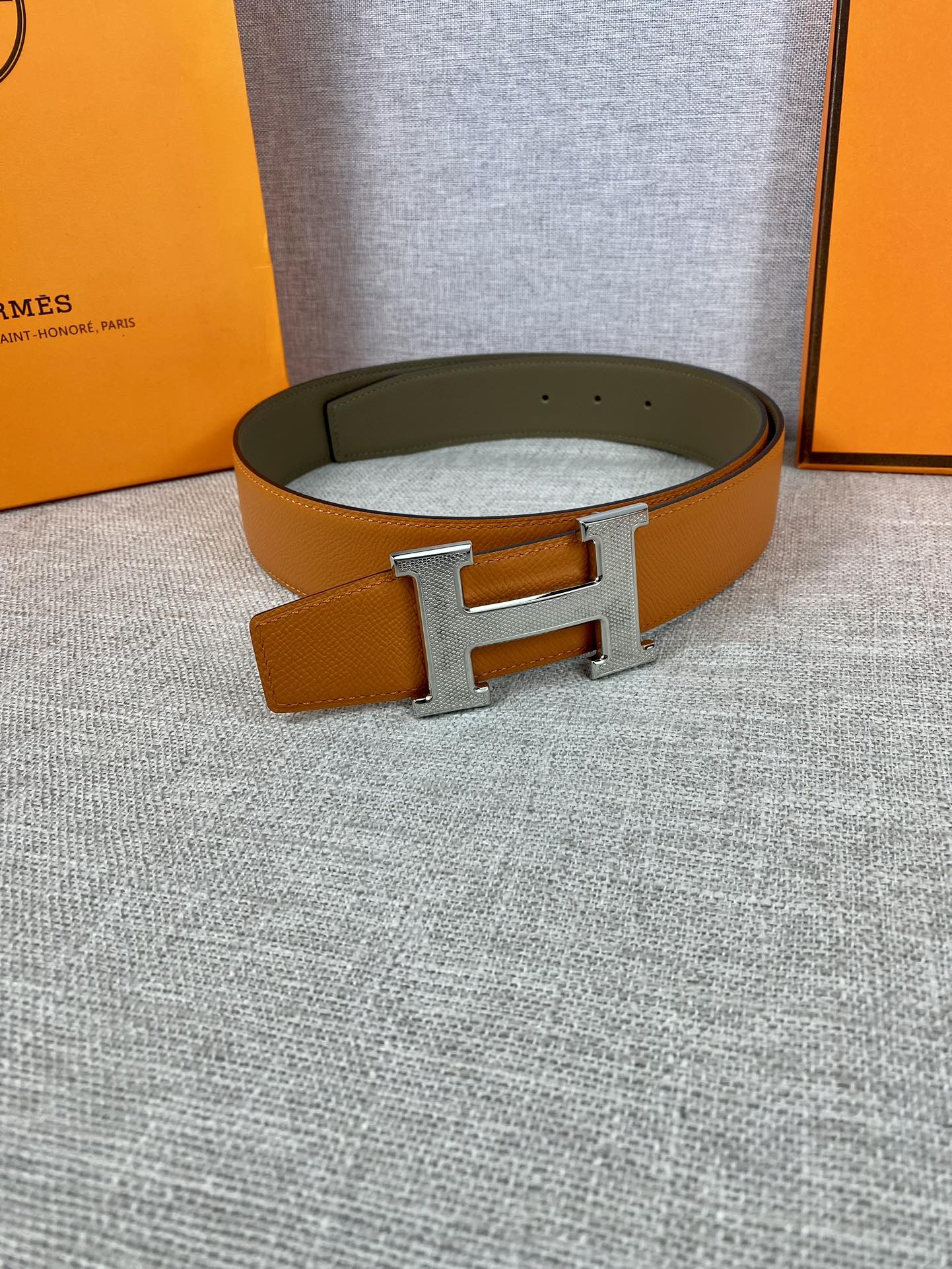 Two-tone leather belt with large silver H buckle on olive strap