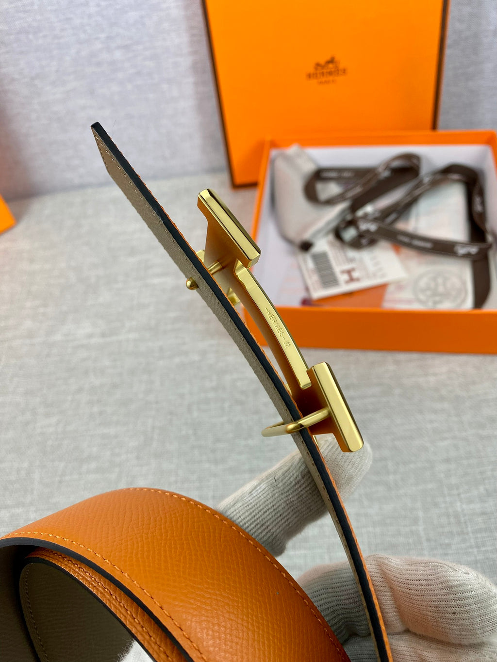 Orange leather belt with gold H buckle hardware and dark edge