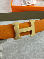 Orange leather belt with large gold H buckle, close-up on metal prong