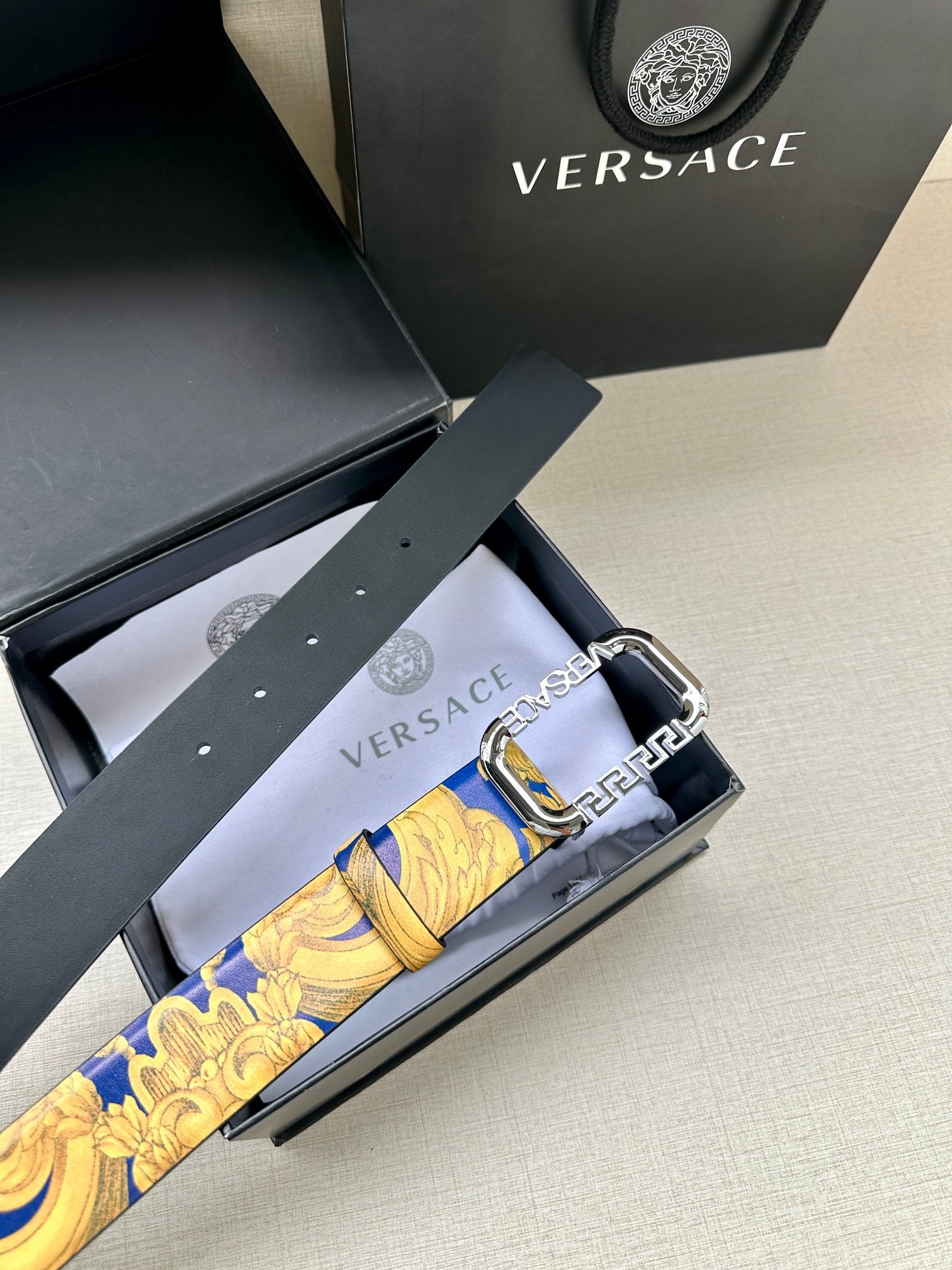 Versace belt in box: blue and gold patterned strap with silver-tone buckle.