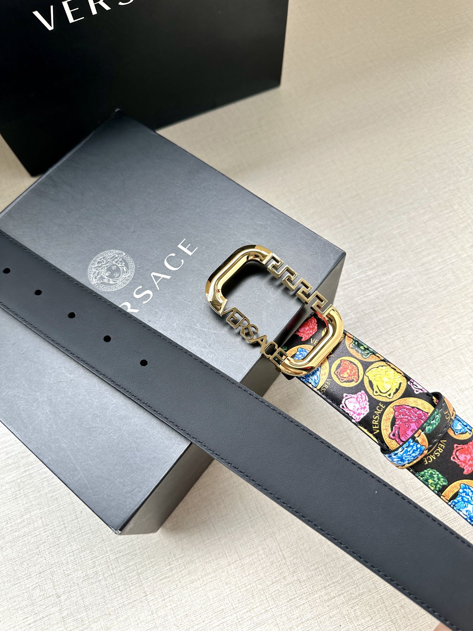 Versace belt detail: ornate gold buckle and multicolor pattern on a dark leather strap
