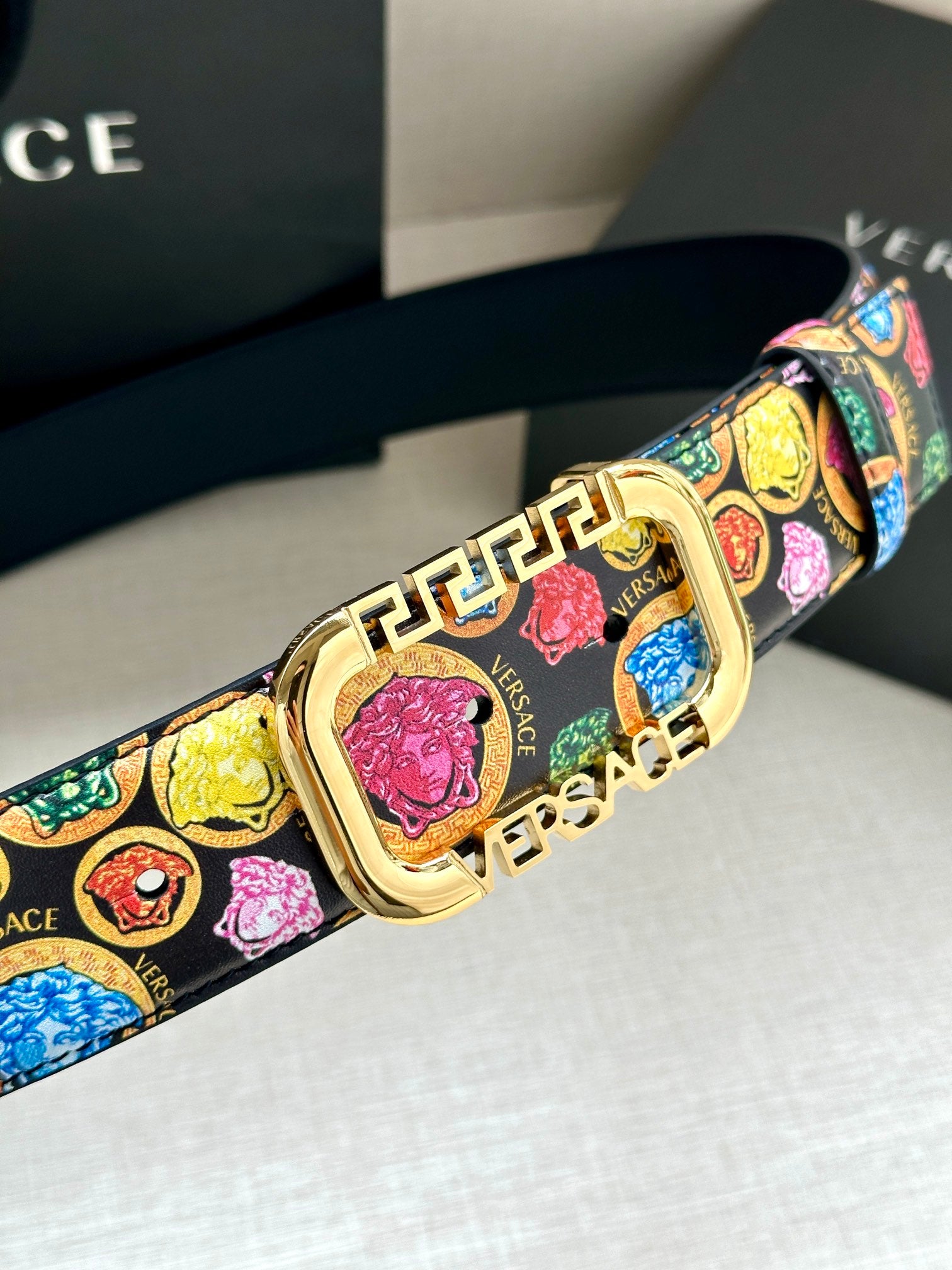 Versace belt close-up with multicolor logo-medallion print and gold-tone buckle