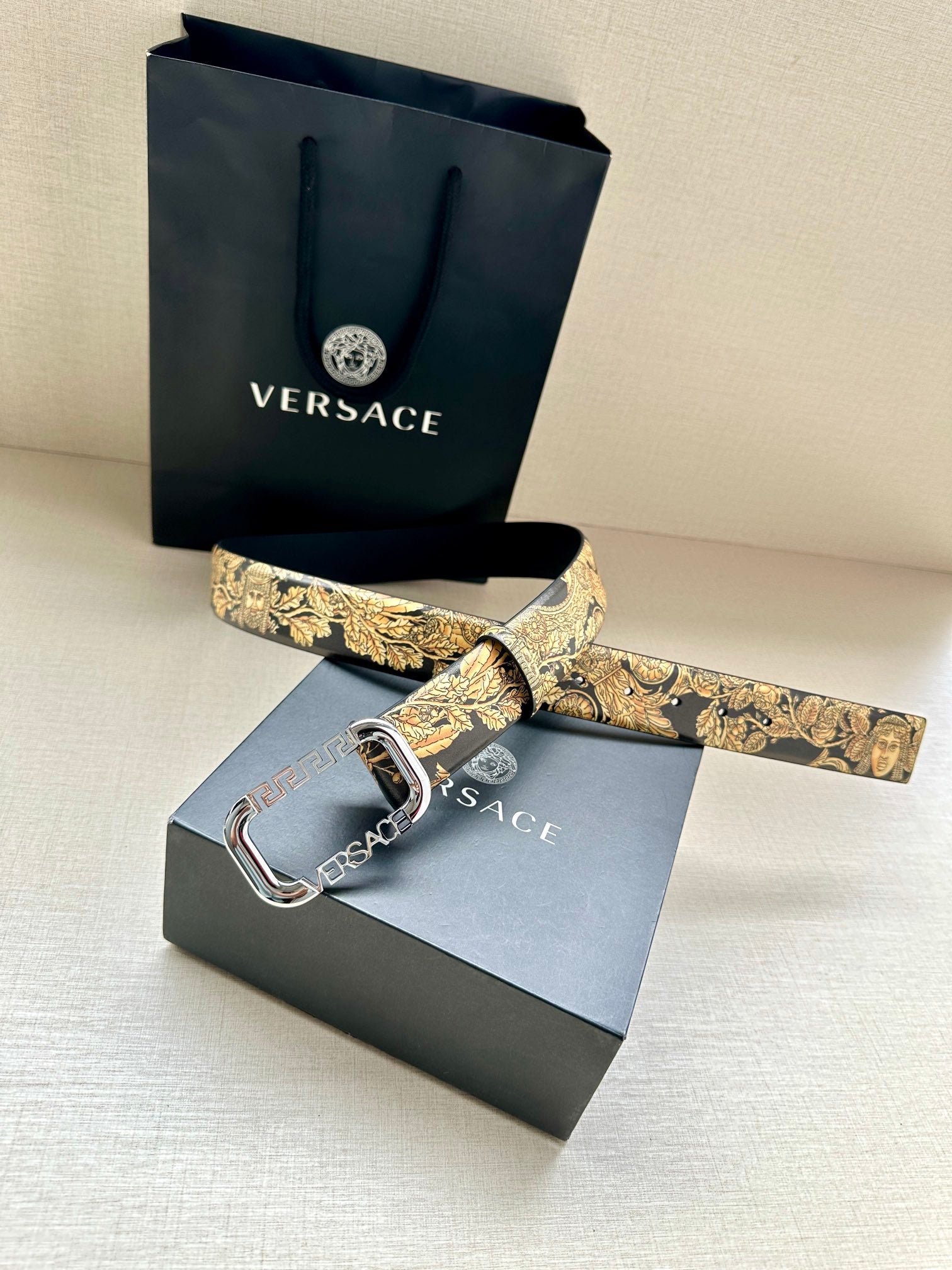 Versace belt with gold baroque print strap and silver buckle, laid flat