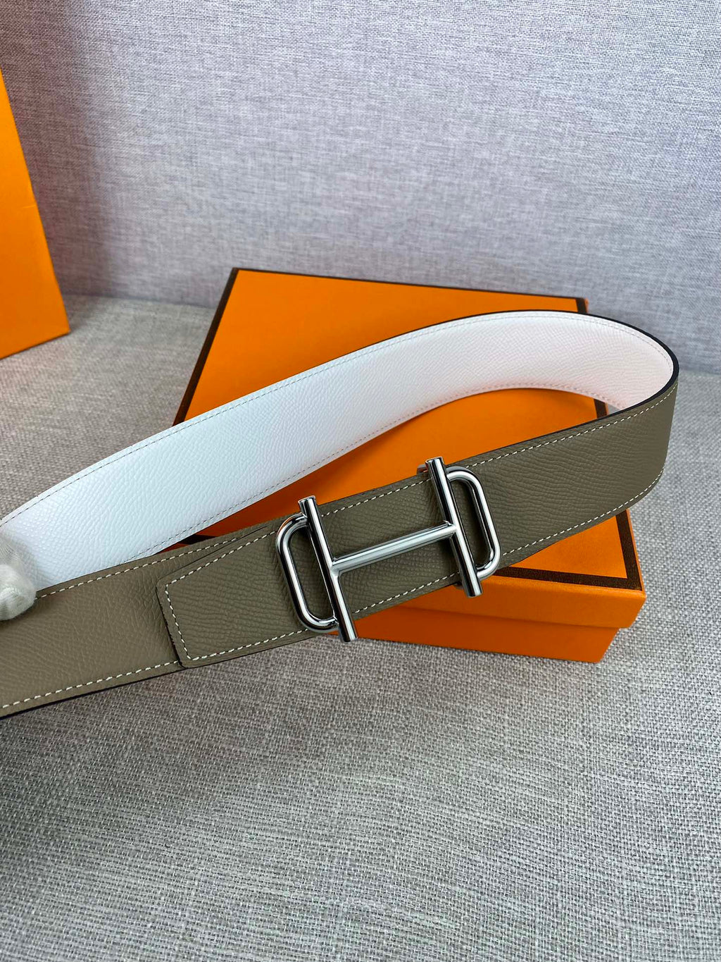 Hermes belt with white leather strap and gold-tone buckle over olive backing