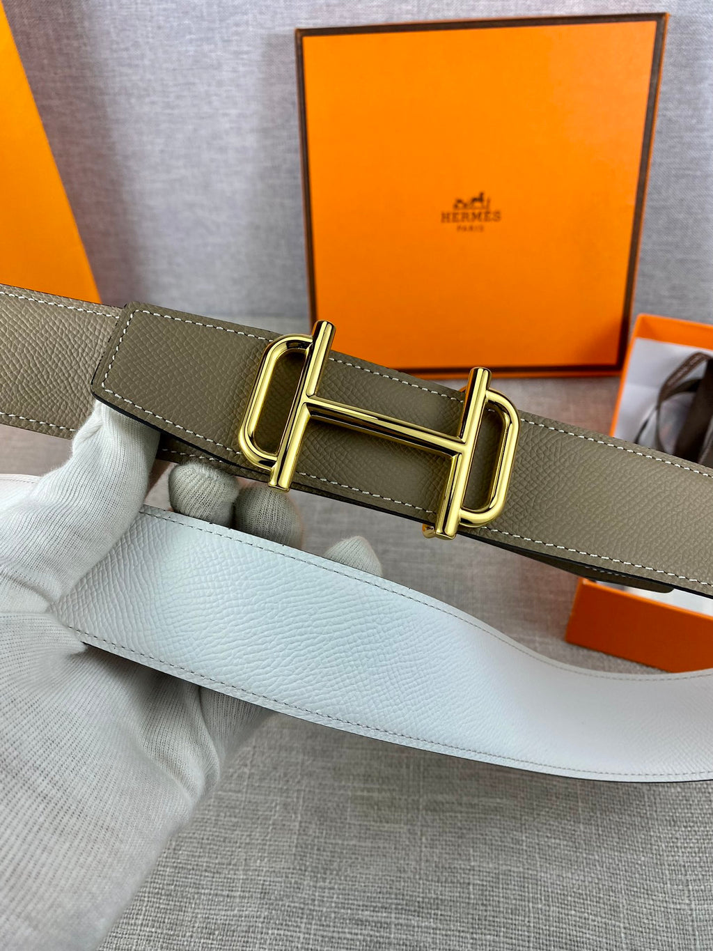 Hermes belt on olive strap with double-prong gold buckle, close-up on clasp