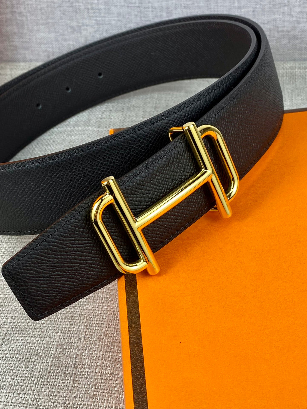 Hermes belt close-up: dark textured leather with gold-tone double-prong buckle
