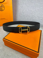 Hermes belt with dark textured leather and gold-tone buckle, laid flat