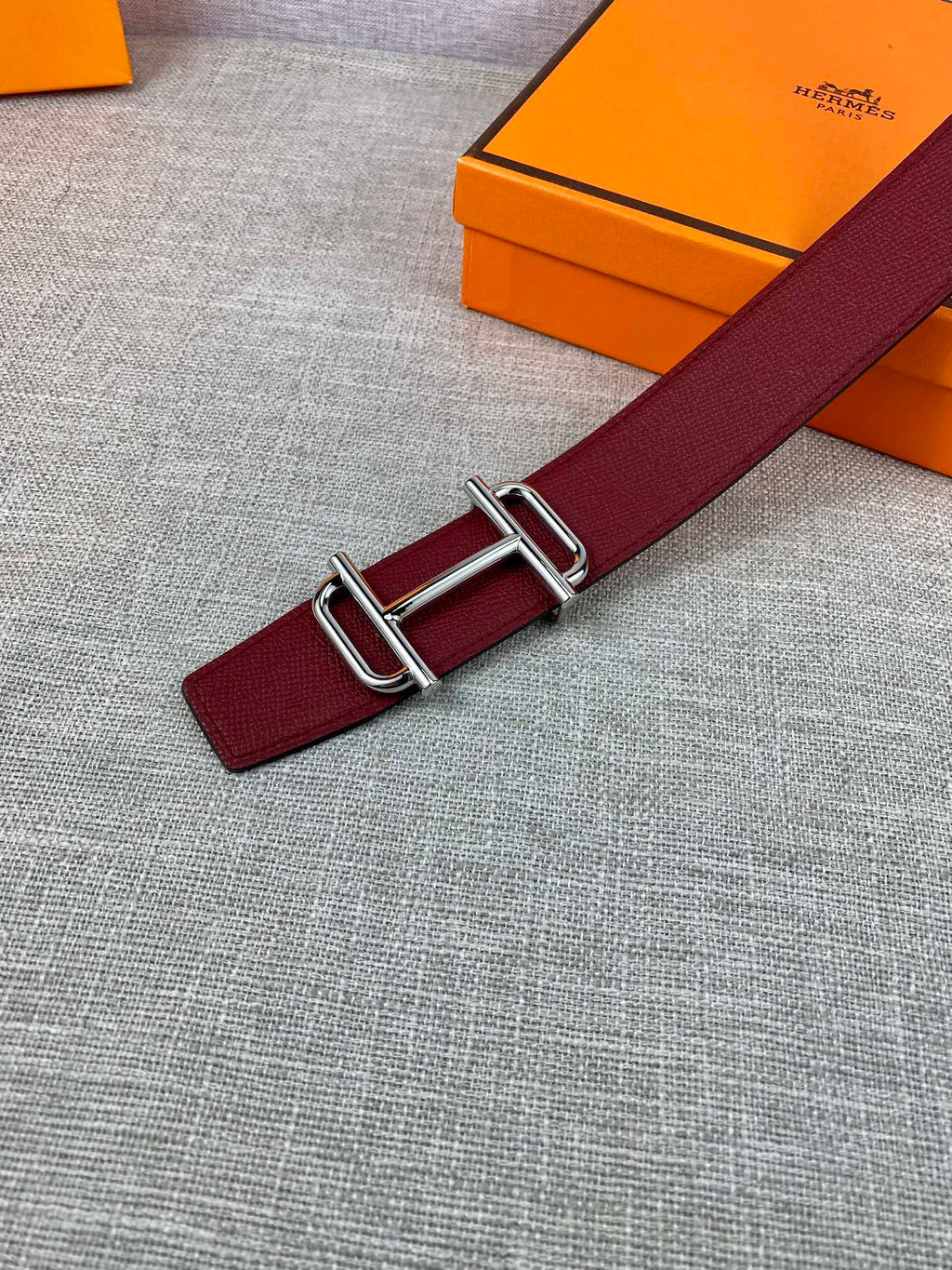 Burgundy leather belt detail with metallic rectangular buckle hardware