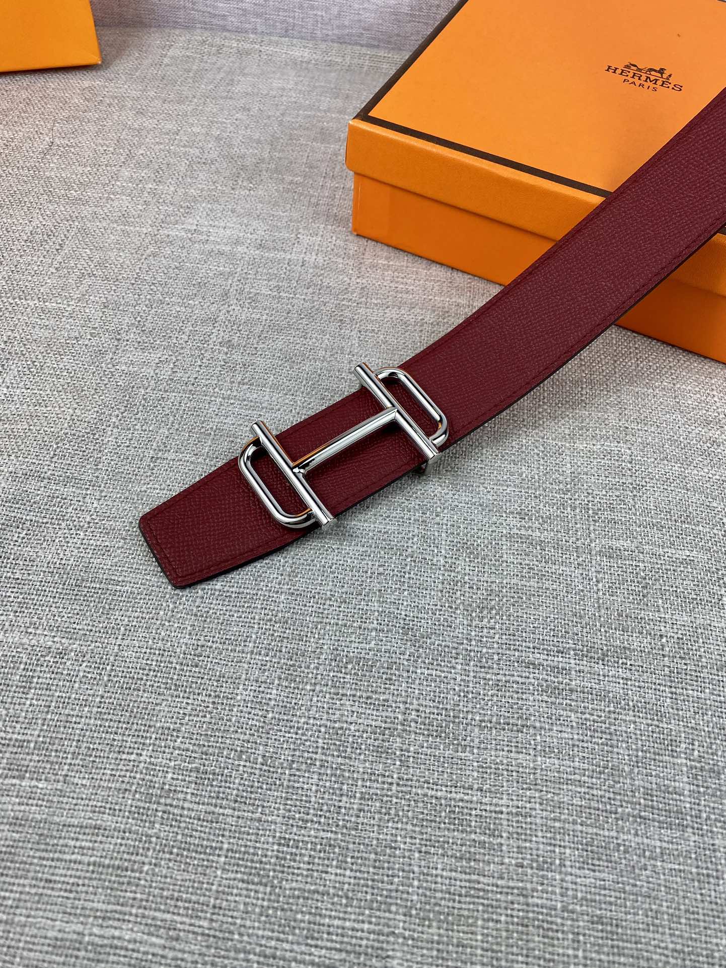 Burgundy leather belt detail with metallic rectangular buckle hardware