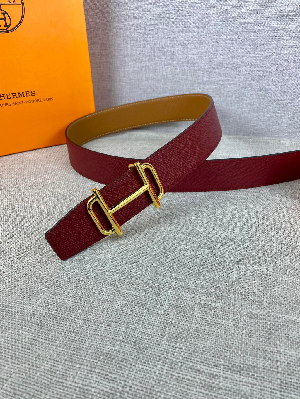 Burgundy leather belt with gold-tone buckle and tan underside