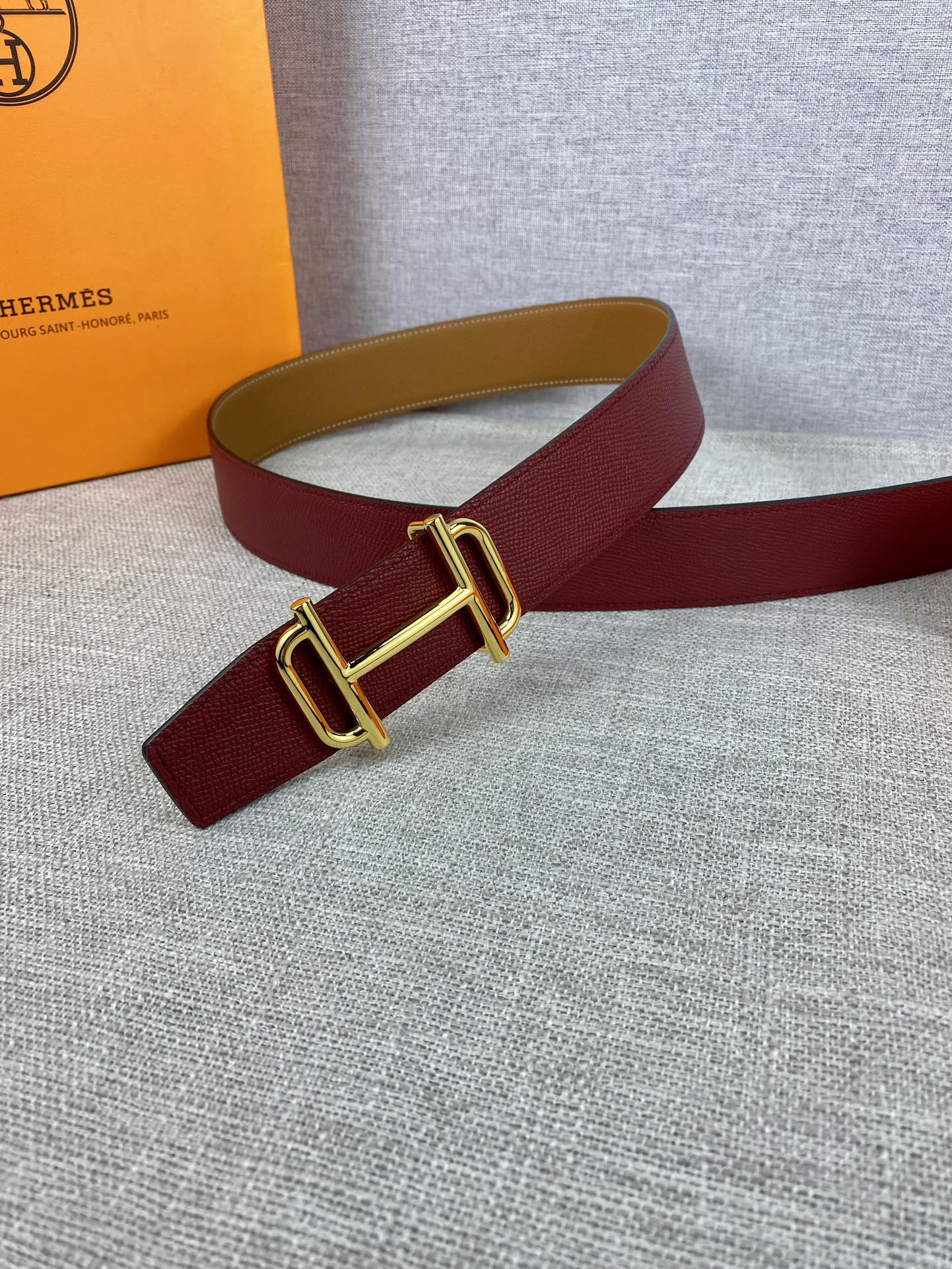 Burgundy leather belt with gold-tone buckle and tan underside