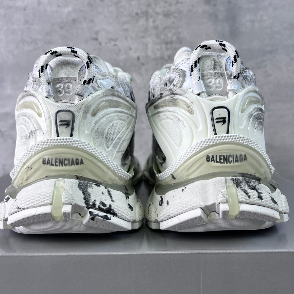 Unisex white sneakers showing heel branding and black graffiti-style side accents