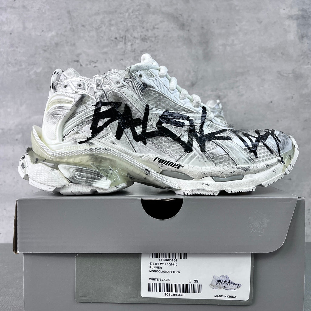 Unisex white sneakers with black graffiti-style print, lace-up, on a shoe box