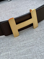 Hermes belt close-up with dark strap and large gold-tone H buckle