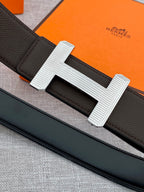 Hermes belt close-up: dark strap with engraved silver-tone H buckle
