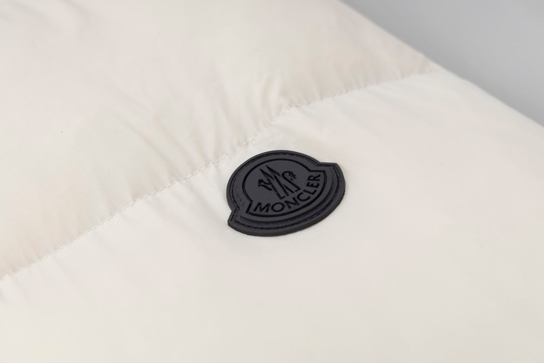 Cream puffer jacket patch logo on quilted fabric panel.