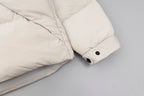 Cream puffer jacket sleeve cuff with black snap buttons and quilted quilting.